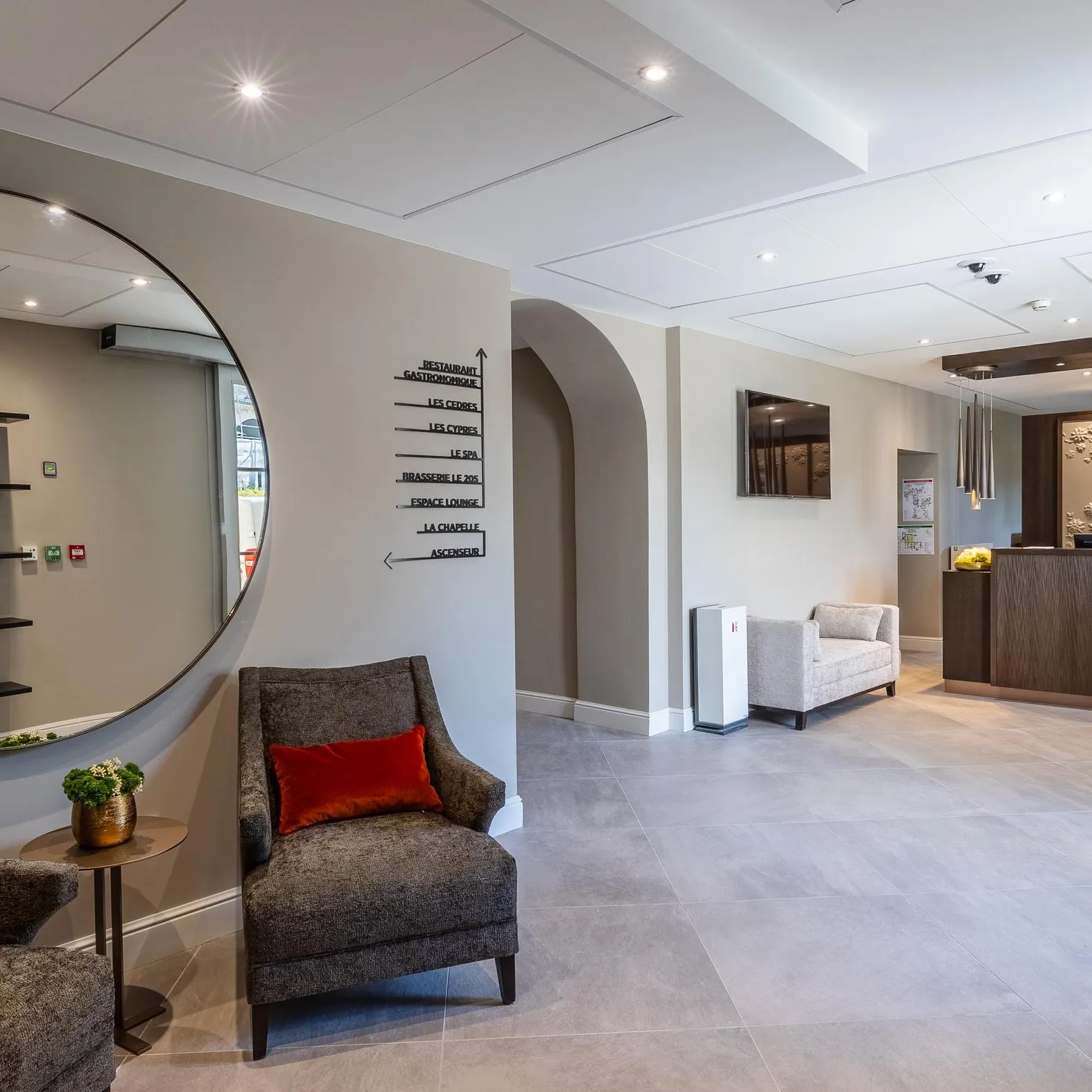 Espace intérieur moderne avec fauteuils, table basse, comptoir de réception et panneaux directionnels sur le mur