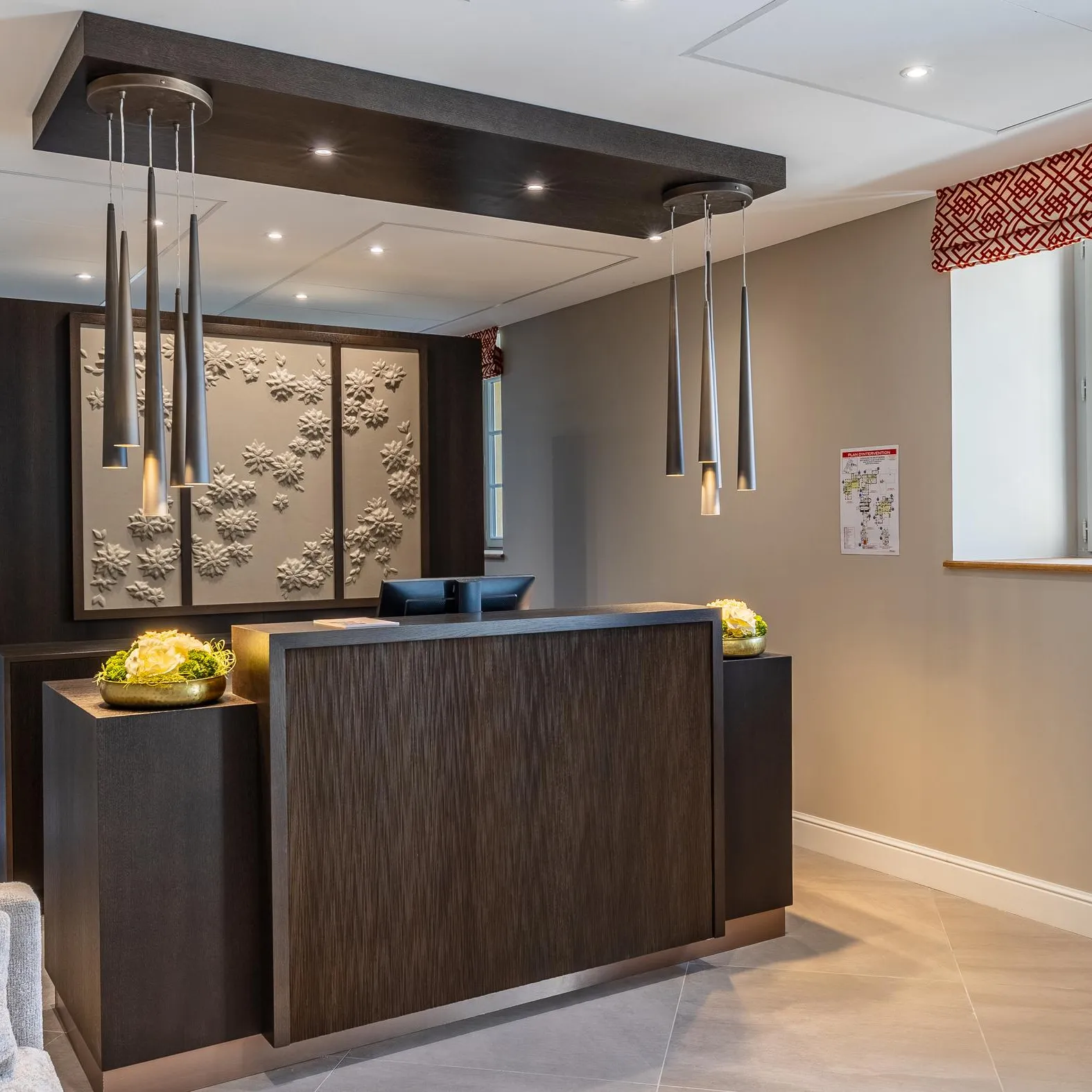 Réception moderne avec un comptoir en bois sombre, des luminaires suspendus et une décoration murale florale