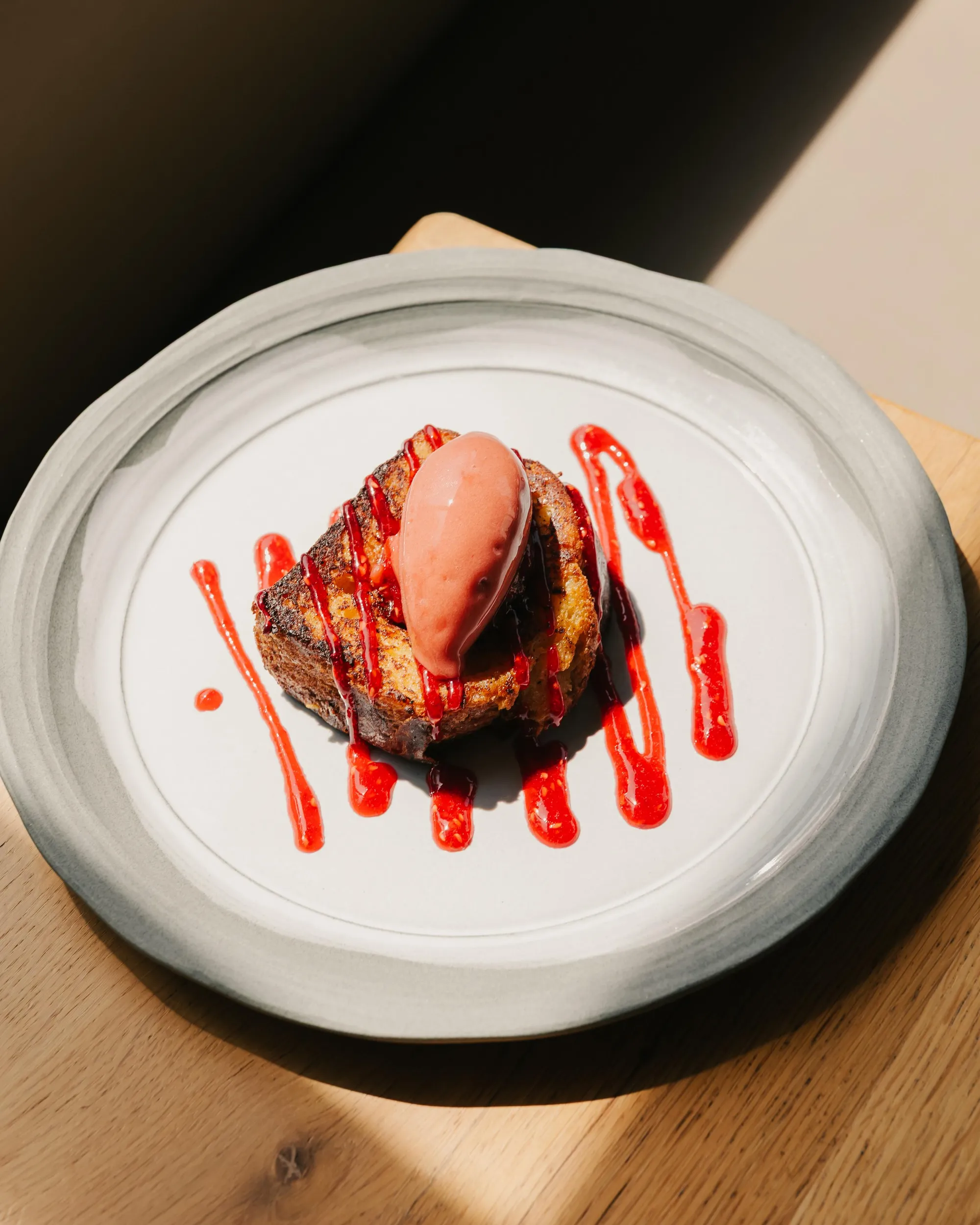 A dessert consisting of a cake with an ice cream scoop and a red sauce on a white plate.