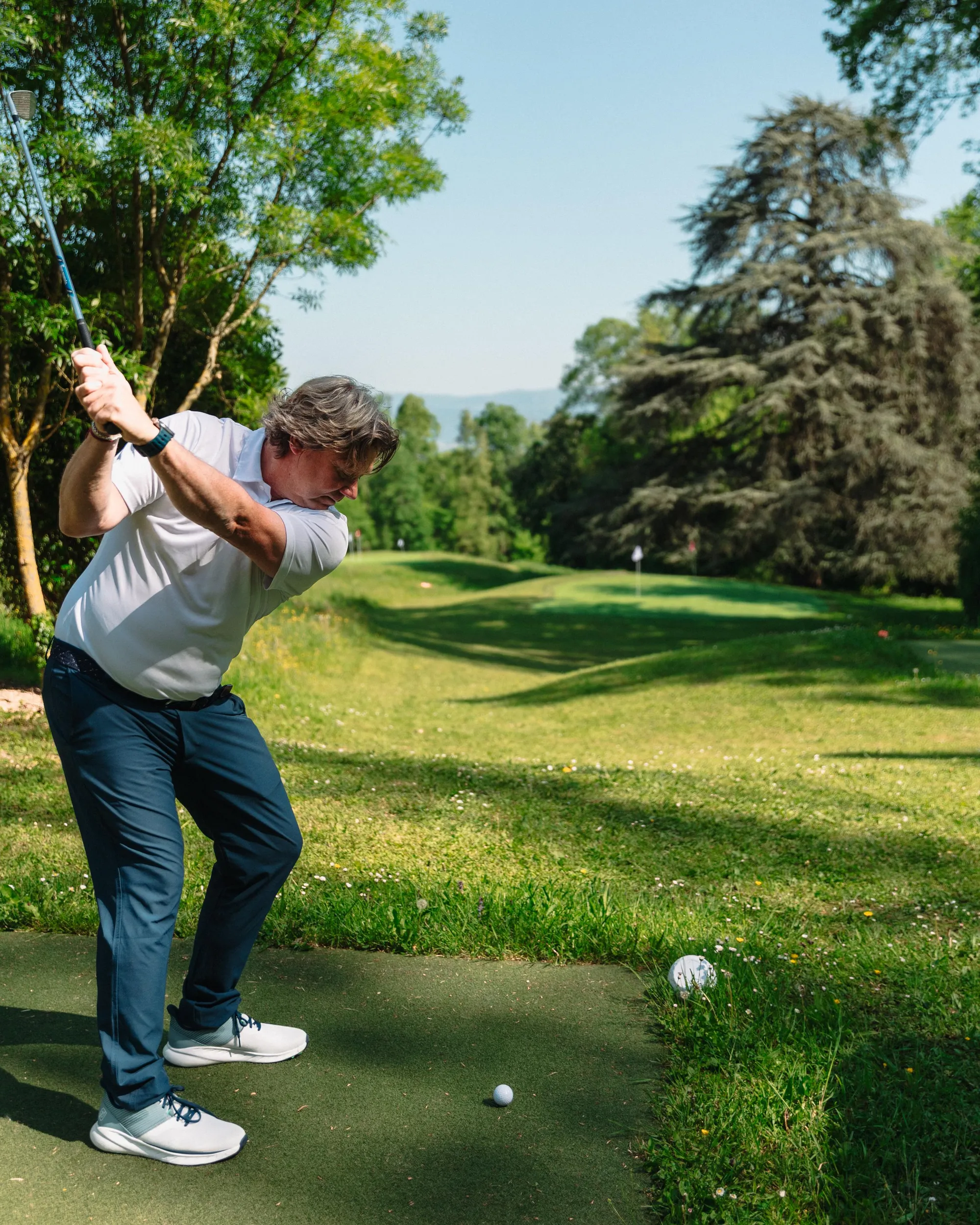 Un homme en train de jouer au golf sur un parcours entouré d'arbres et de verdure