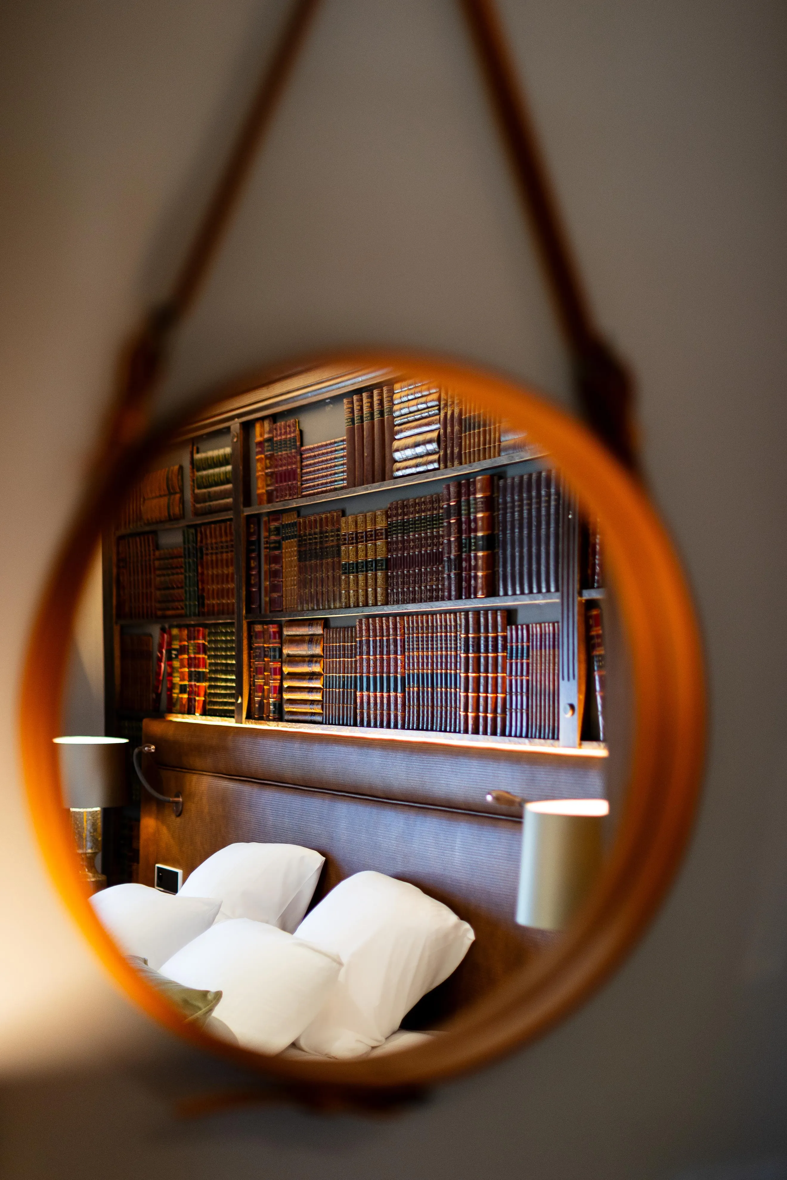 Gesehen durch eine kreisförmige Linse eines Regals mit alten Büchern und eines Bettes mit weißen Kissen