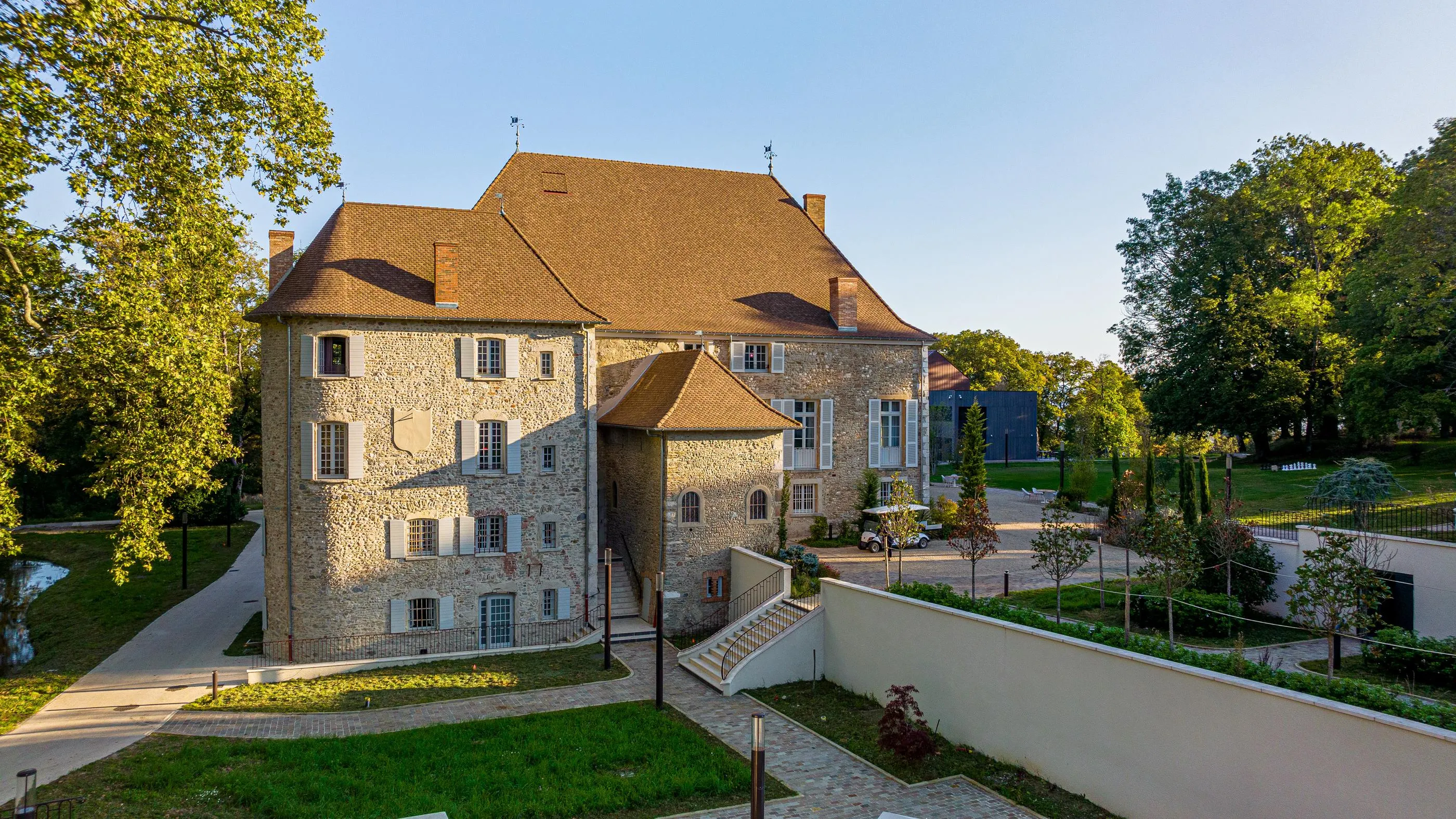 Steinhaus mit Ziegeldach, umgeben von Bäumen und Gärten, von einem erhöhten Punkt aus gesehen