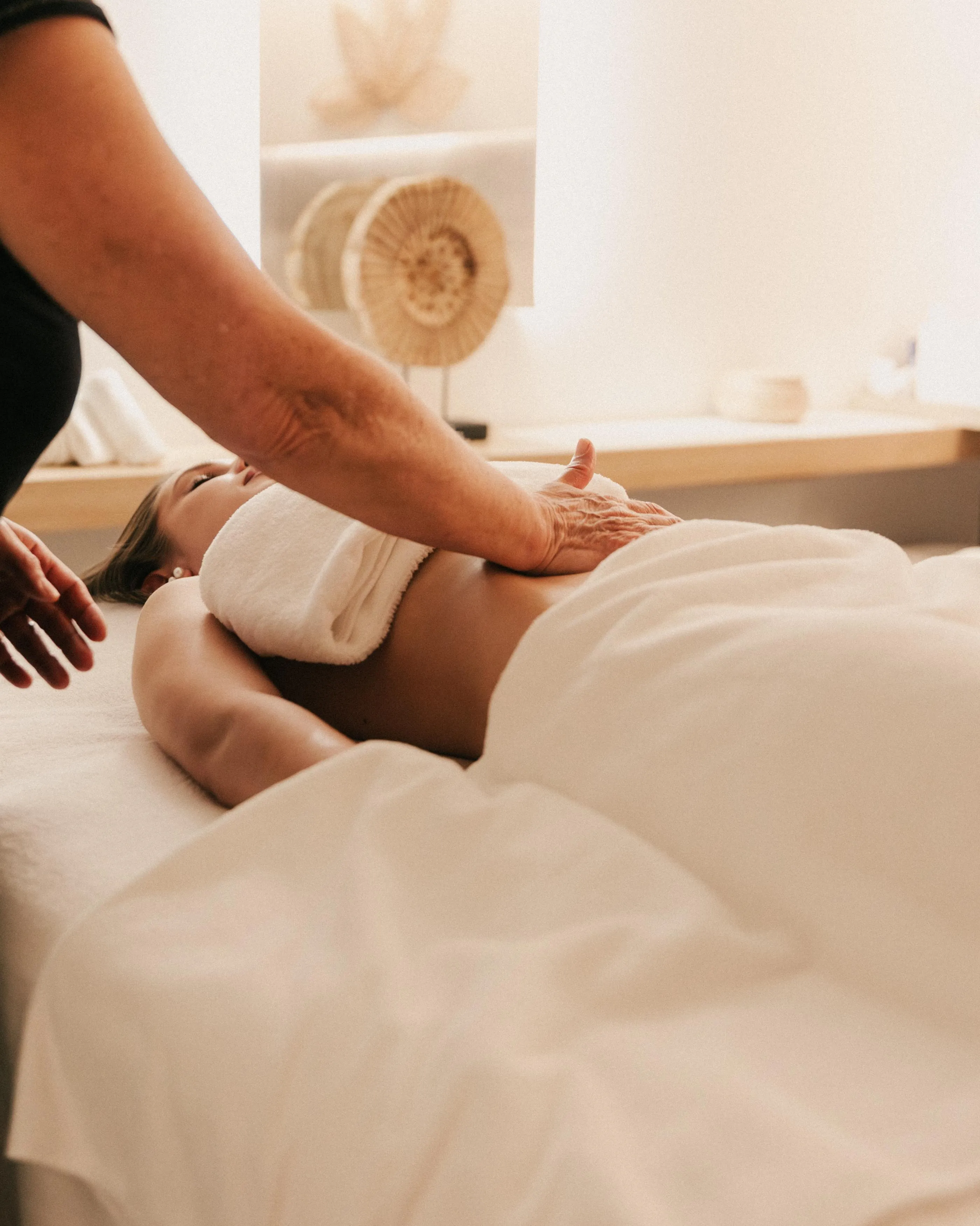 A person receives a back massage in a relaxing setting with a shell-shaped wall decoration.