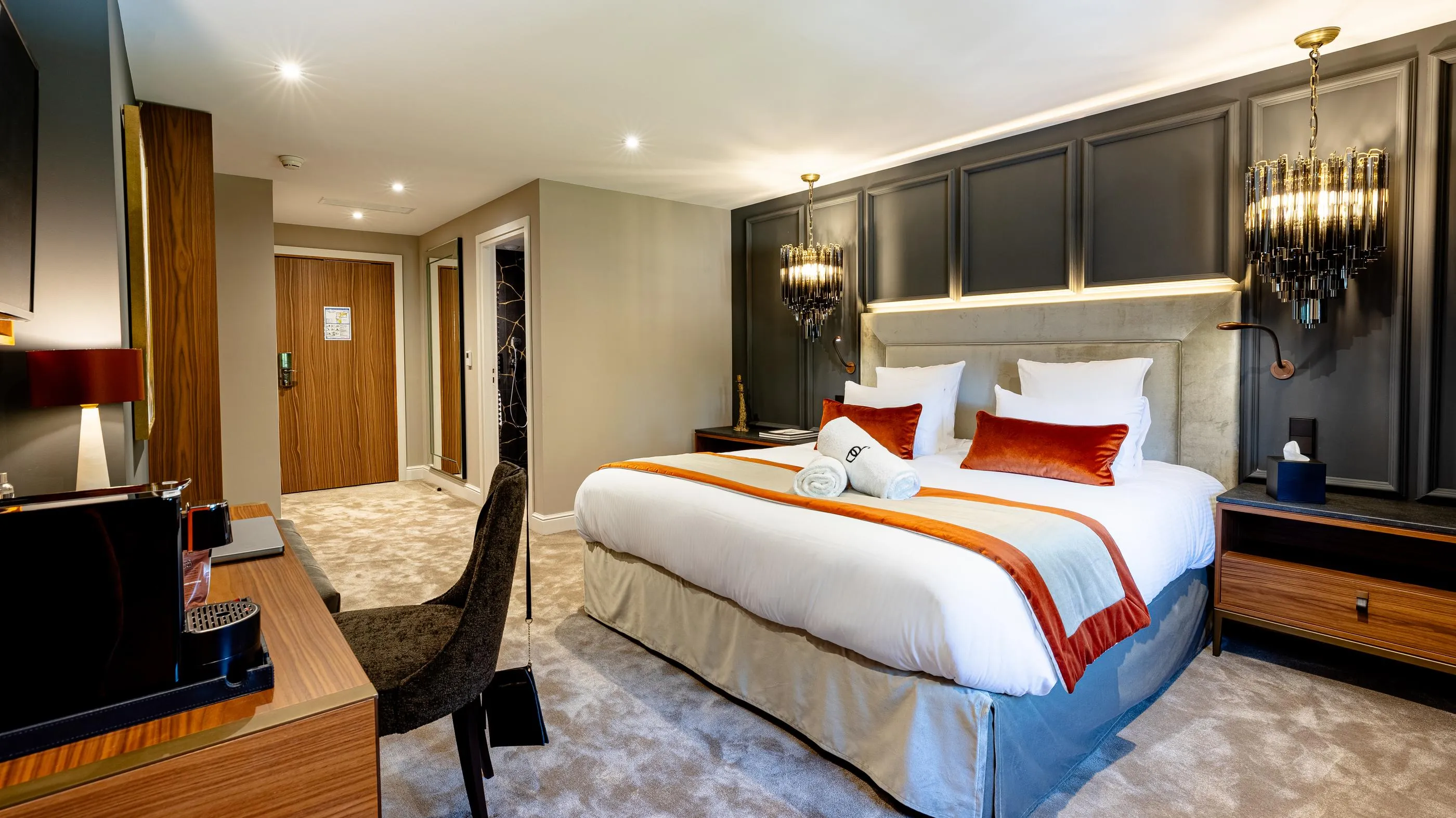 Hotelzimmer mit einem Doppelbett, einem Nachttisch, einem Stuhl und moderner Beleuchtung
