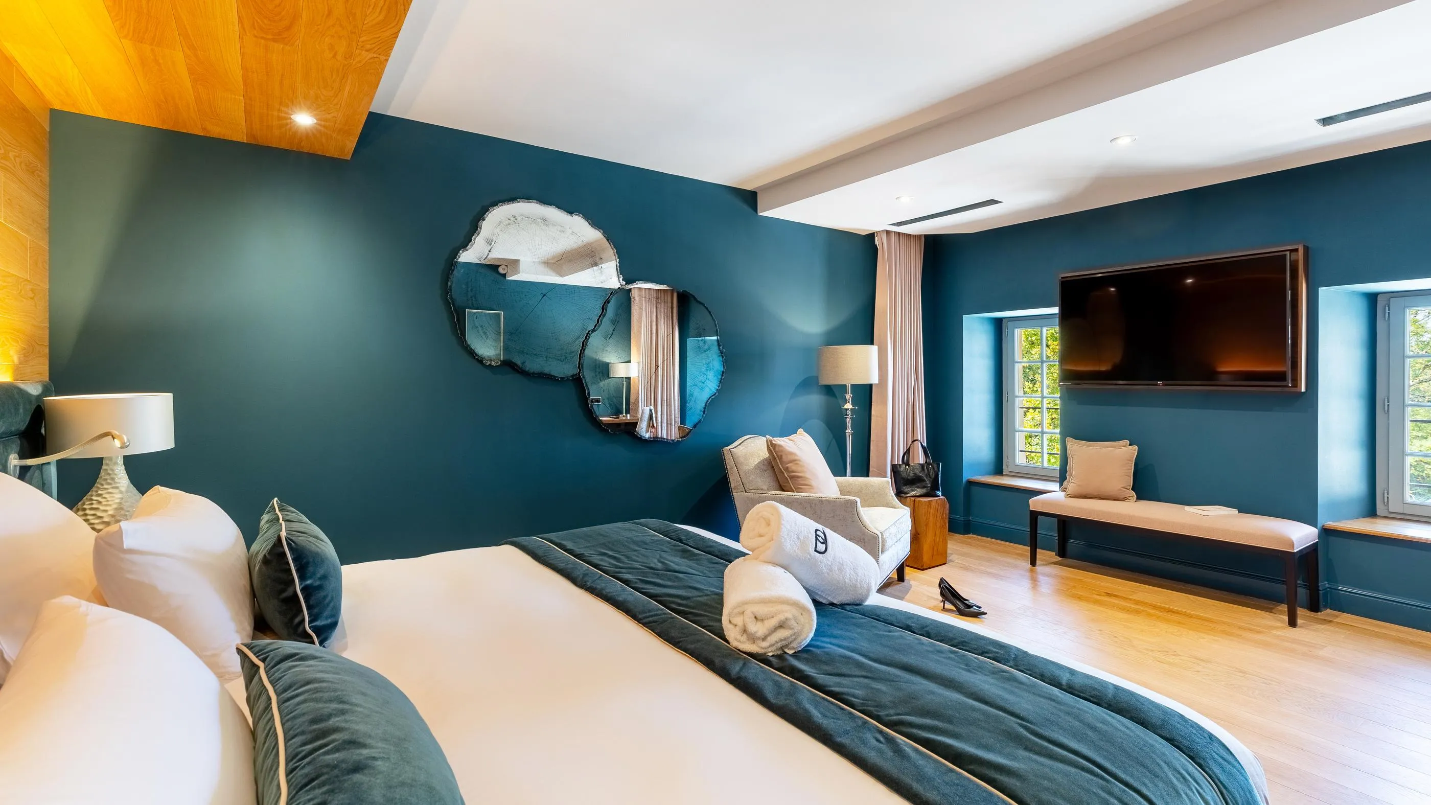 Moderne Zimmer mit Bett, Sessel, Fernseher, Wandspiegel und Fenstern nach außen
