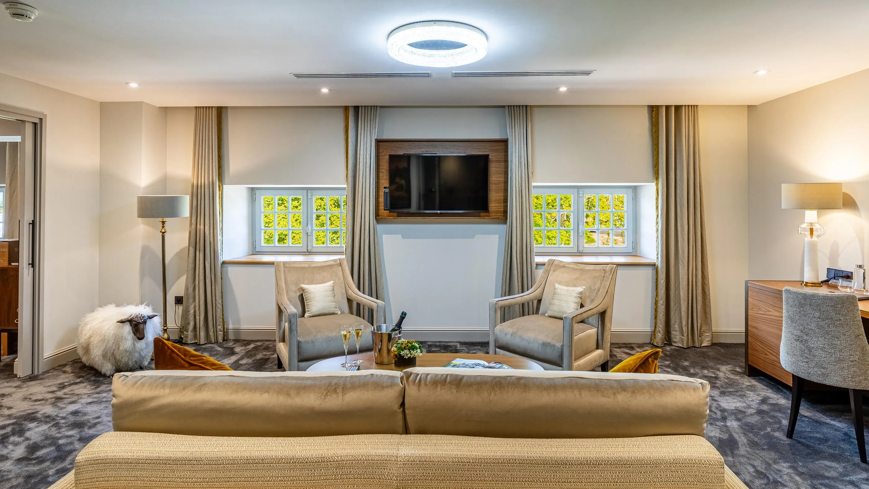 Living room with sofa, armchairs, coffee table, lamps and windows with open curtains