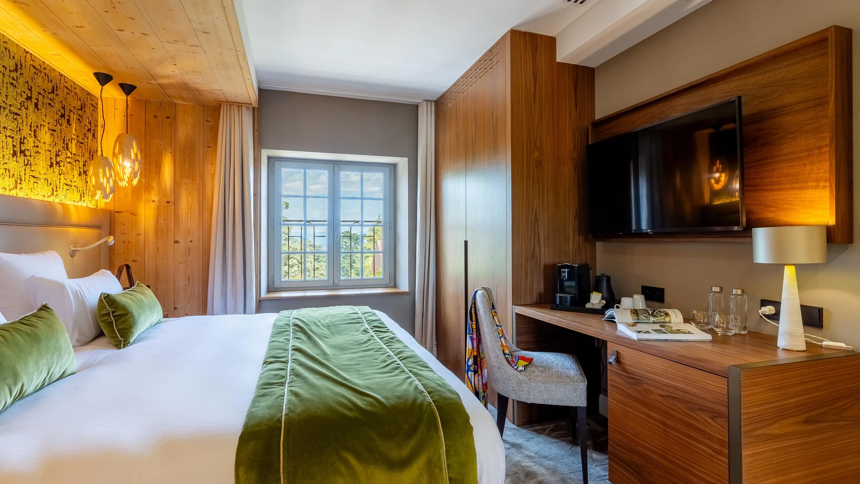 Hotel room with a double bed, a work desk, a television, and a window overlooking the outside.