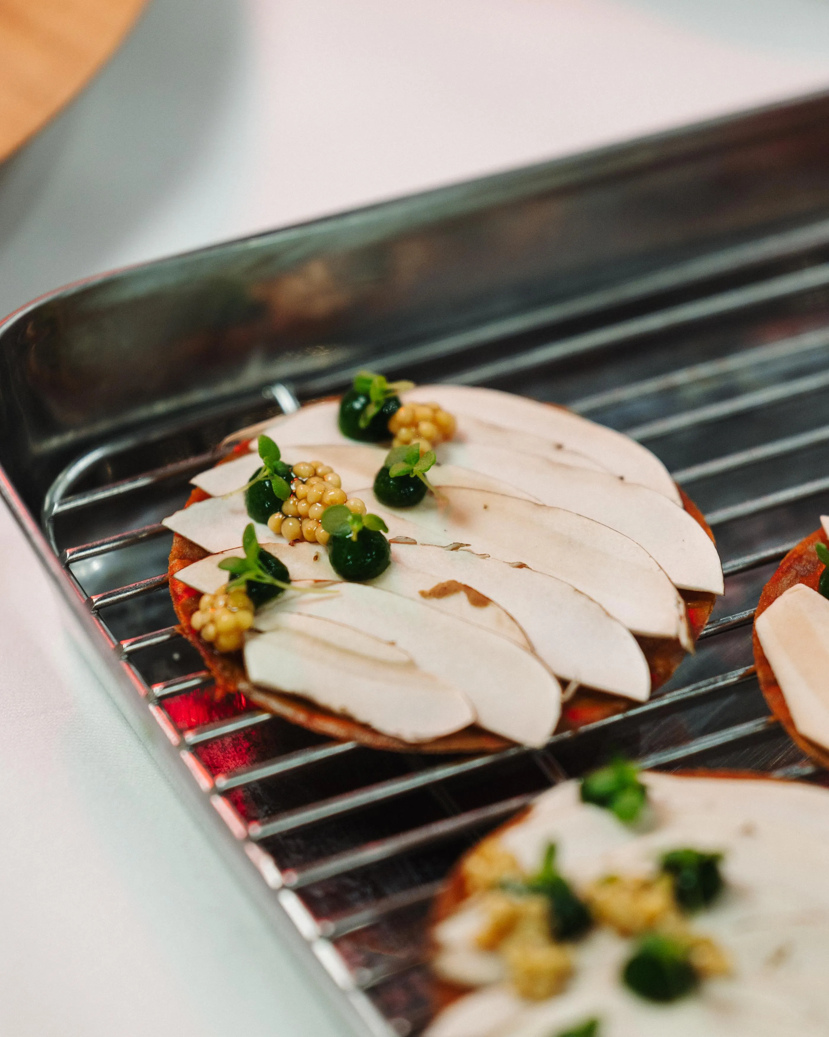Des tranches de champignons garnies de caviar et de micro-pousses cuisent sur un grill