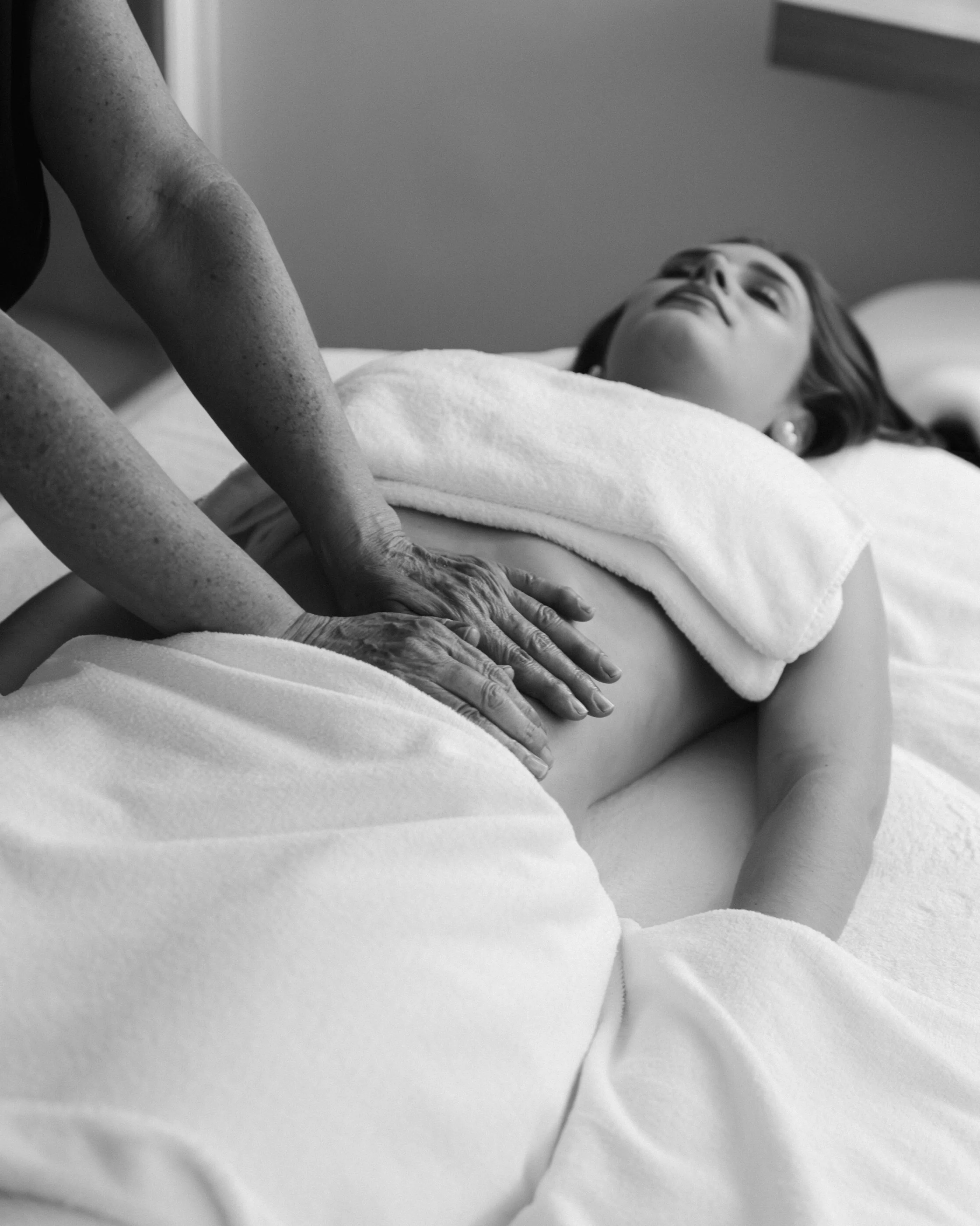 Une personne allongée sur un lit reçoit un massage des mains et des avant-bras